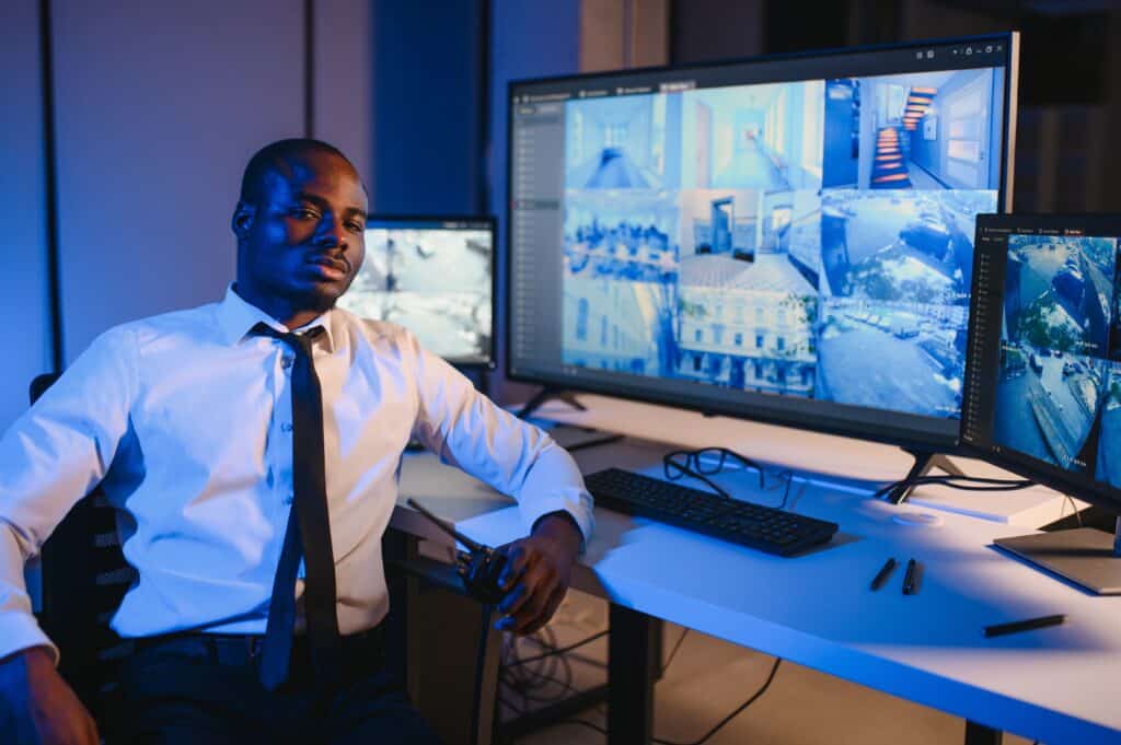 Why Physical Security Solutions Are Essential for Modern Operational Environments 3 Security professional monitoring security cameral systems and operational data from a command center.